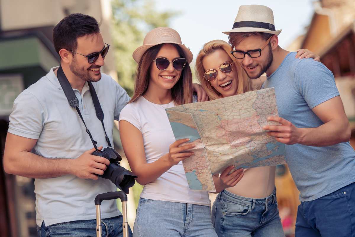 turisti sorridenti due uomini e due donne con mappa in mano